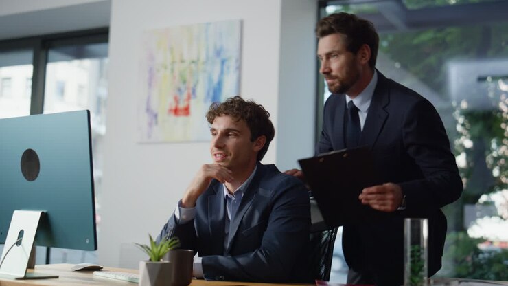 Un mentore serio dà consigli a un manager in un ufficio moderno. Colleghi al lavoro
