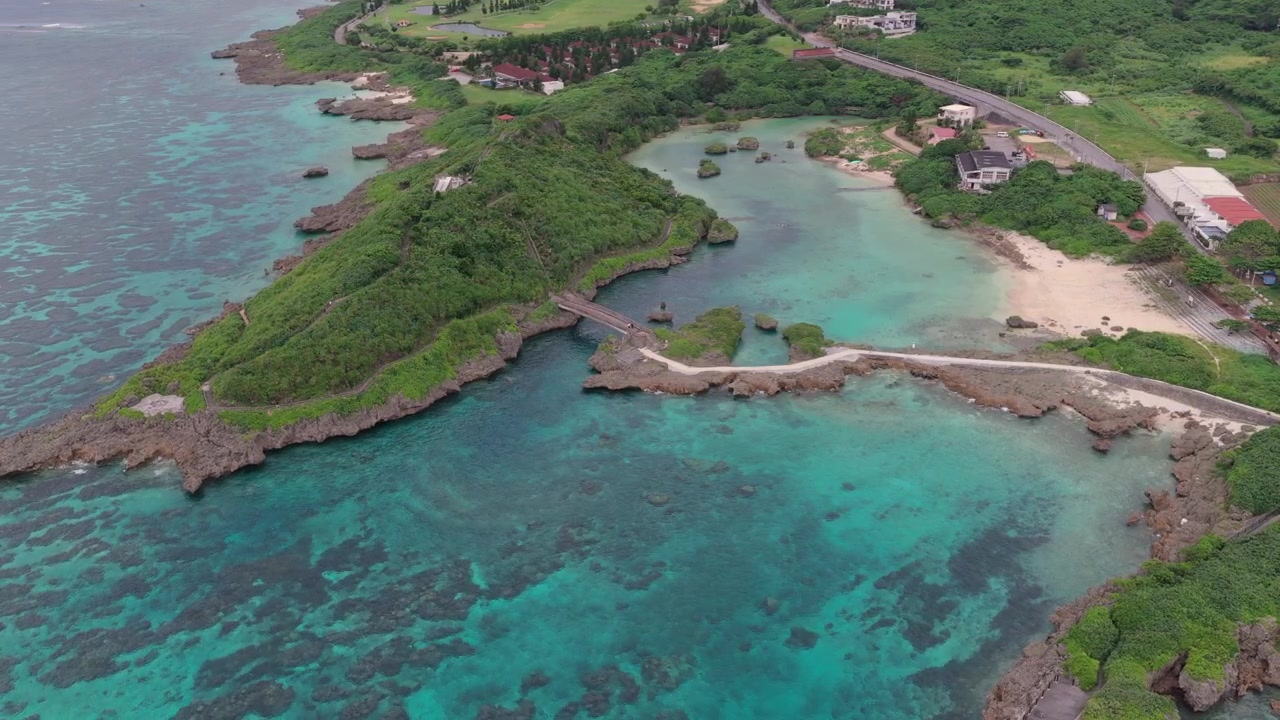 Ripresa aerea orizzontale con panoramica a sinistra e spostamento a destra sopra il Giardino Marino di Imgyaa, il Villaggio Corallo e l'insenatura costiera turchese, Miyakojima, Okinawa, Giappone.