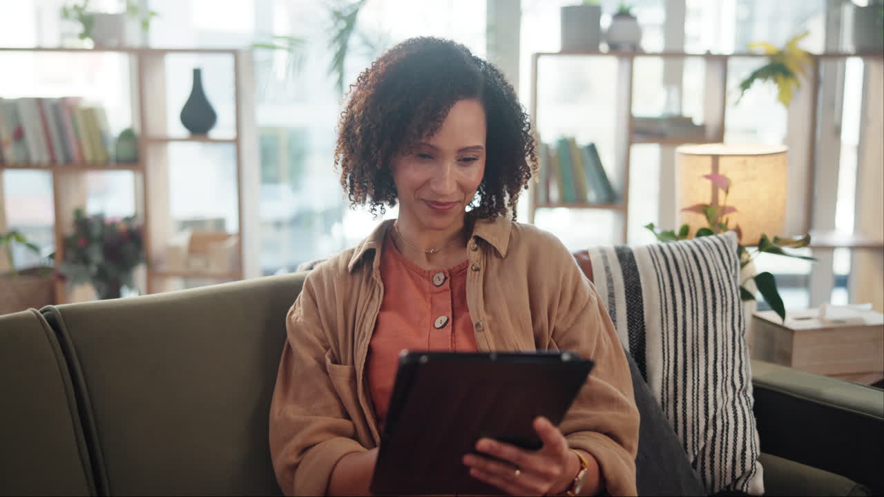 Woman using a tablet on a couch in a living room