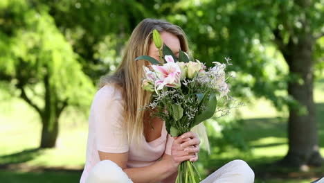 pretty girl smelling bouquet of flowers in the park