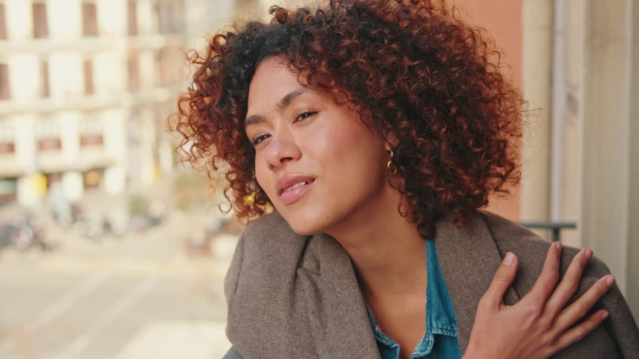 Peaceful Young Woman with Curly Hair on City Balcony