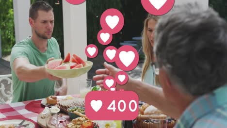 Animation-of-social-network-heart-icons-and-rising-number-over-caucasian-family-dining-in-garden