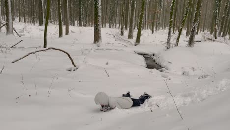 Girl-Rolls-Down-In-Heavy-Snow-In-The-Forest-During-Winter-In-Germany---wide-shot