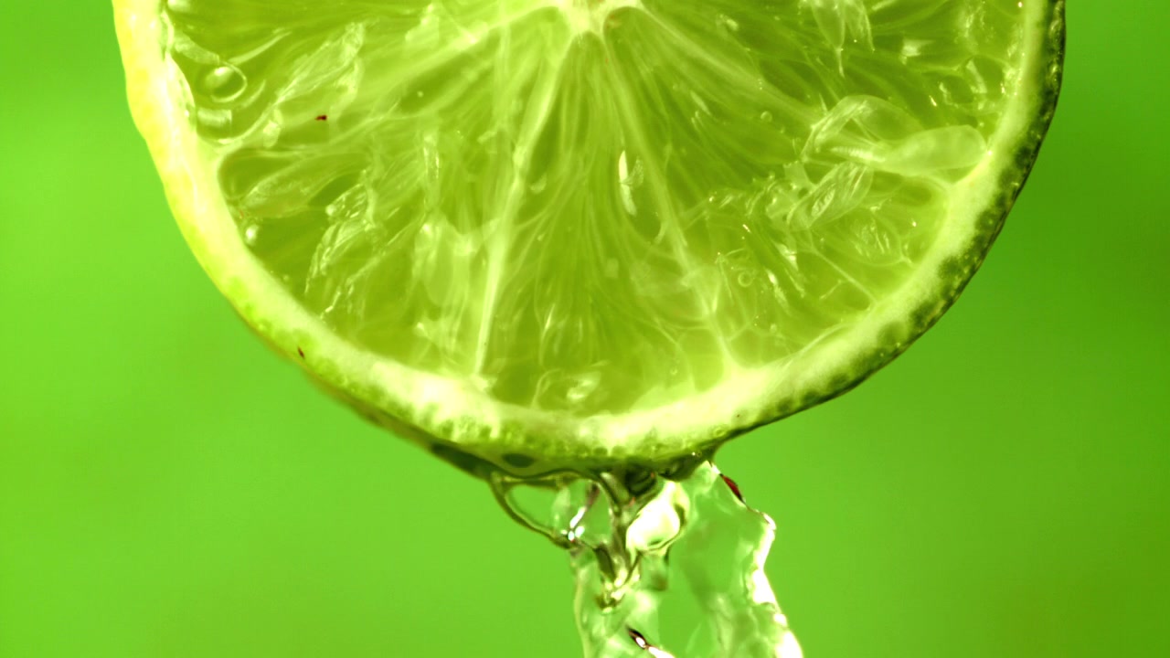 Vand drypper fra en frisk limeskive i slowmotion