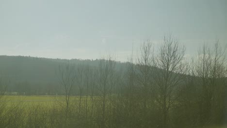 inside a moving german ice train with a view of barren trees and distant hills