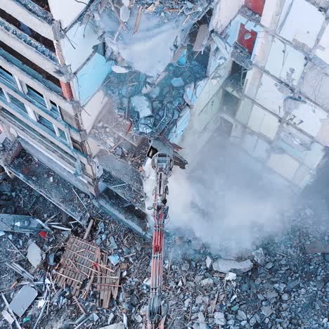demolishing machinery breaks the floors and walls of the ruin. debris falling down with heavy dusty clouds. rising over the ruins and debris