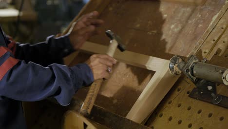 closeup shot of a worker assembling a wood frame, furniture manufacturing plant in pakistan