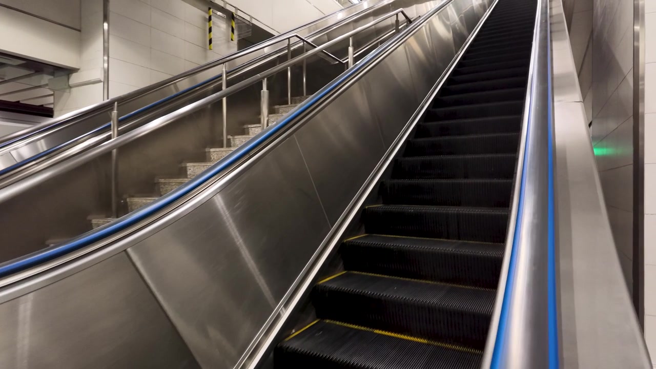 Lavvinkelbillede af tomme metalrulletrappetrin, der bevæger sig opad på en metrostation