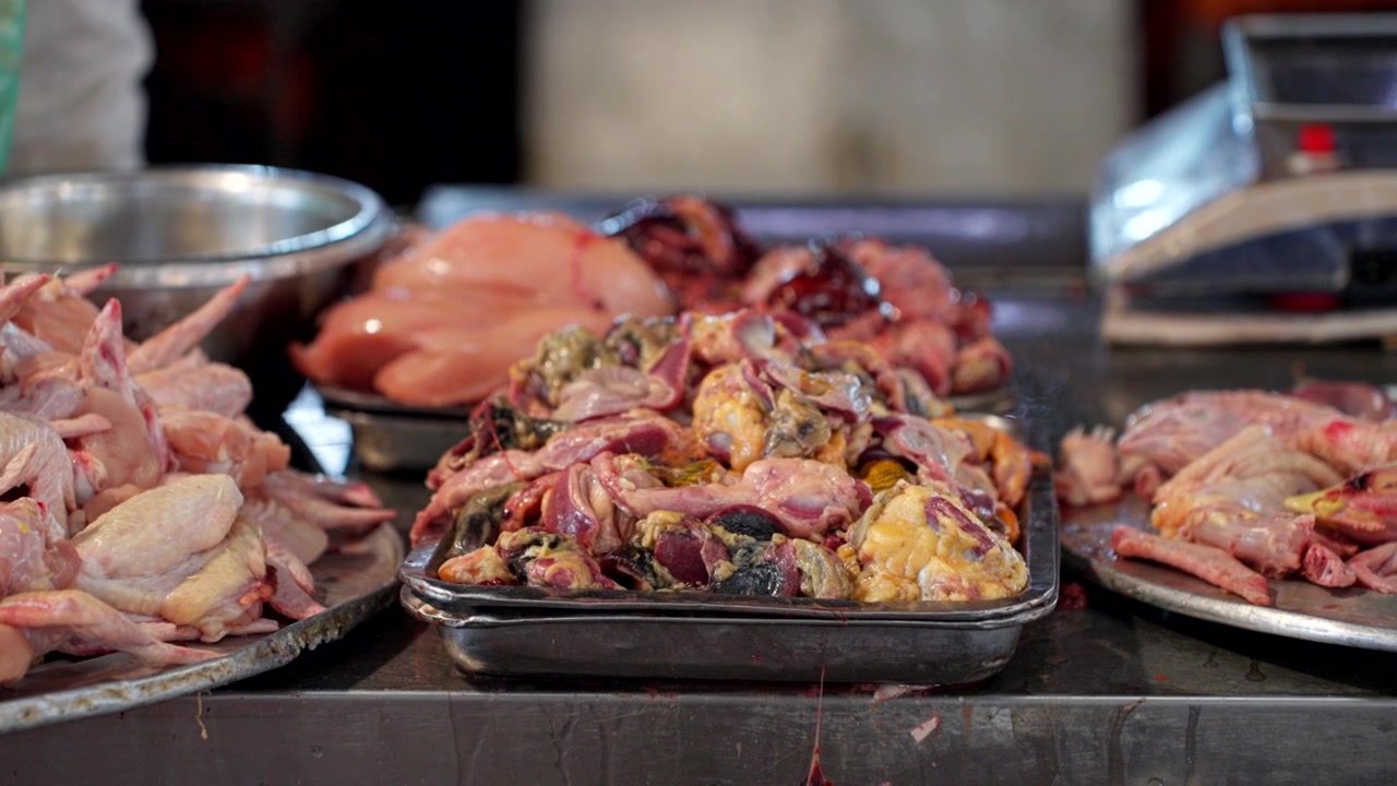 Close-up detalhado de várias partes de carne de aves em um movimentado mercado úmido em Sapa: pés de galinha, coxas de frango e pedaços crus recém-abatidos