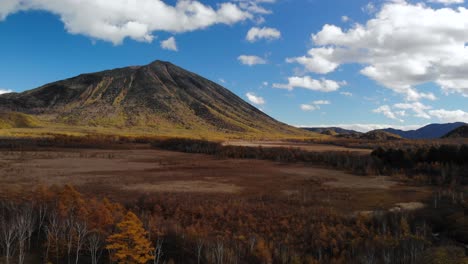 Slow-aerial-forward-over-wide-open-autumn-marshland-with-beautiful-blue-sky