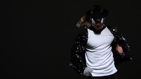 stylish man in sparkling jacket and fedora dancing on dark background