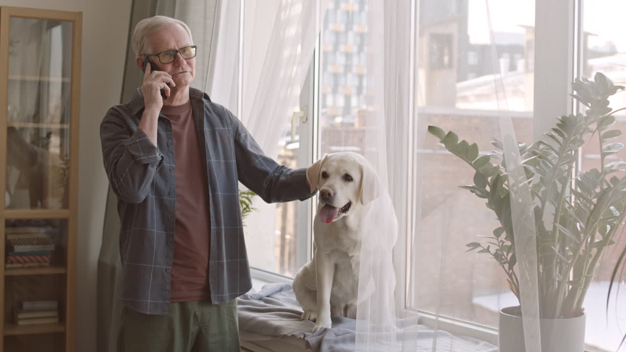 Elderly Man Petting His Dog during Phone Call