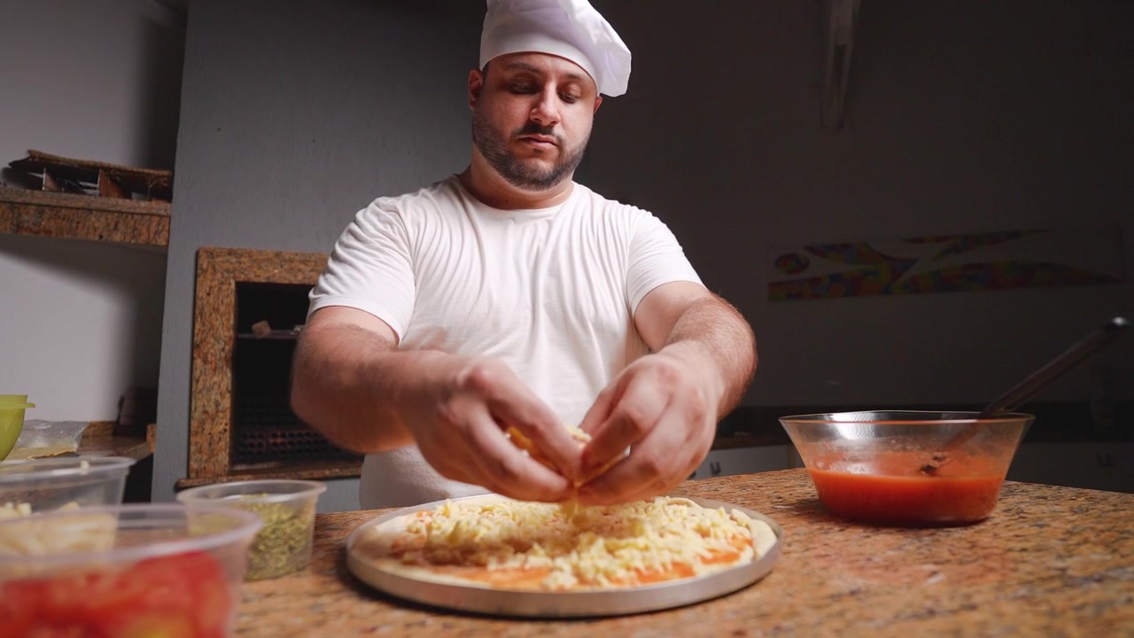 Uno chef prepara con maestria una pizza aggiungendo uno strato di formaggio grattugiato sull'impasto della pizza condito con una saporita salsa di pomodoro