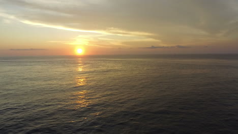 aerial view of surfers on surfboards in rough sea at sunset