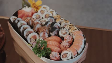 colorful variety of sushi rolls served in wooden tray with herbs