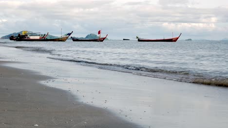 Fishing-boats-moored-along-a-windswept-beach-during-the-day-in-southern-Thailand