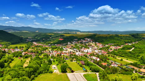 green valley village view. bright day reveals a picturesque village surrounded by lush greenery and mountains under a clear blue sky