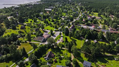 Establishing shot of Kolka settlement with trees, fields, rural buildings Latvia