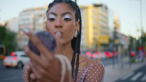 smiling woman checking makeup looking mirror at evening urban avenue closeup