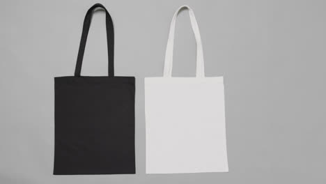 Close-up-of-white-and-black-bags-on-grey-background,-with-copy-space,-slow-motion