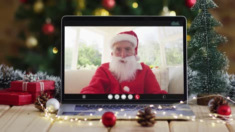 Senior-caucasian-man-in-santa-costume-on-video-call-on-laptop,-with-christmas-decorations-and-tree