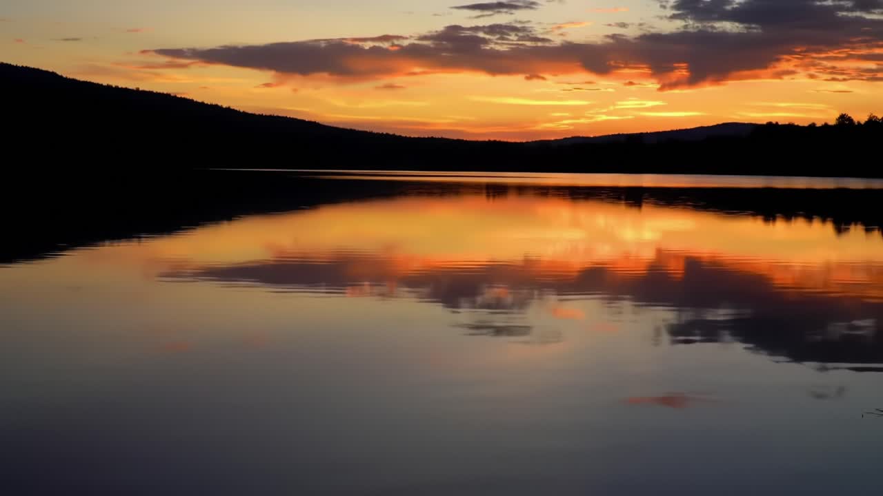 Breathtaking Sunset Over Calm Waters: A Serene Reflection of Colors on the Lake Surface at Dusk