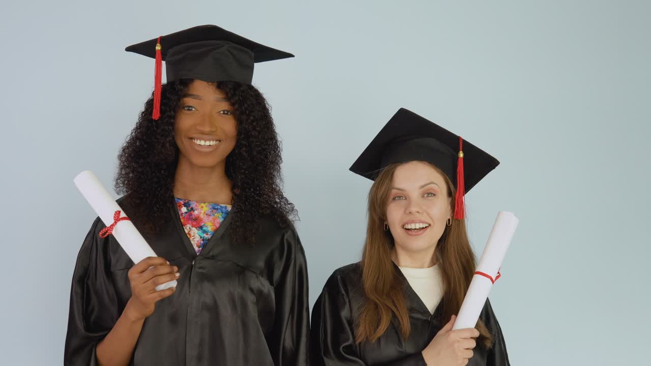 mujeres jóvenes afroamericanas y caucásicas están una al lado de la otra y tienen diplomas educativos.