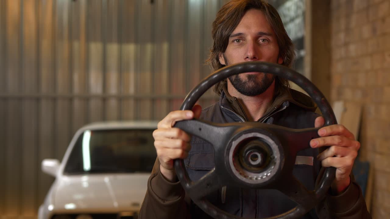 el hombre voltea y gira el volante del coche desconectado y guiñando un ojo, cierre lento