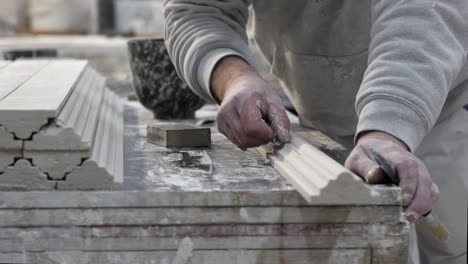 man’s hand working on gypsum profile in mounding workshop