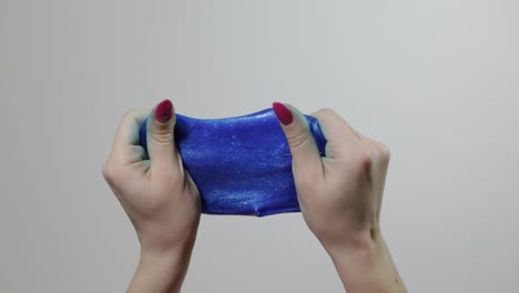 Woman-hands-playing-with-oddly-satisfying-blue-slime-gooey-substance.-Antistress