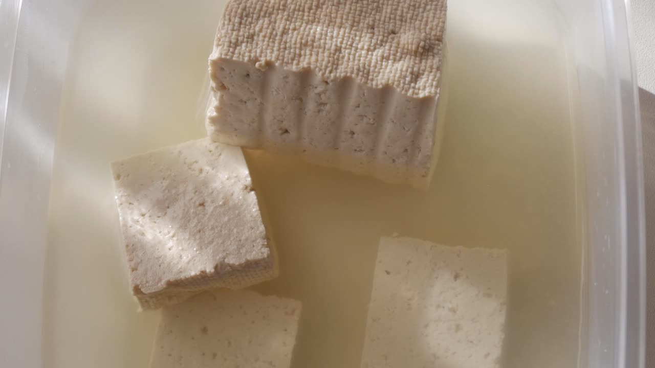 Tofu cubes in liquid, soft texture, natural light, fresh and simple kitchen vibe
