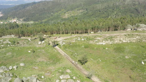 Mountain-Bikers-arduously-climbing-to-Alto-Minho-mountain-top-Portugal---Aerial-Wide-Orbit-tracking-shot