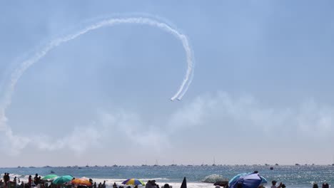 aviones dibujando patrones en el cielo por encima de los visitantes de la playa