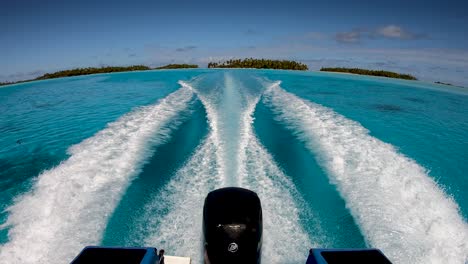 view over the outboard engines of a speedboat flying over the tropical blue lagoon of fakarava, french polynesia. camera tilts up into the blue sky