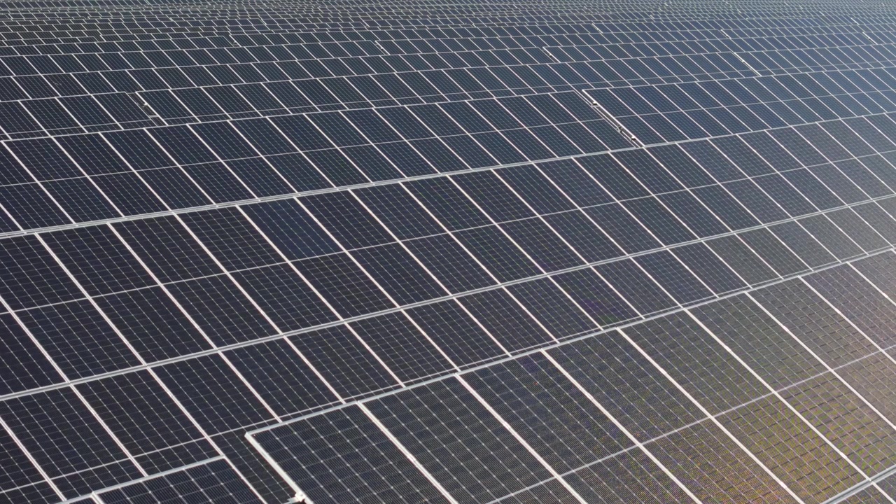 Vista orbitale su un parco solare che mostra pannelli bifacciali di un sito di energia rinnovabile, con una perfetta texture a griglia quadrata.