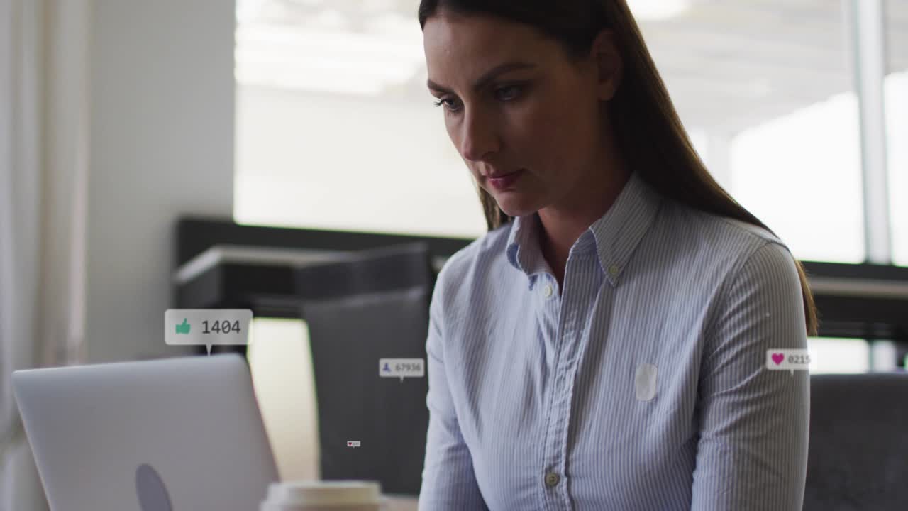 Midadult woman typing on laptop animated social media likes appearing near cup showing engagement