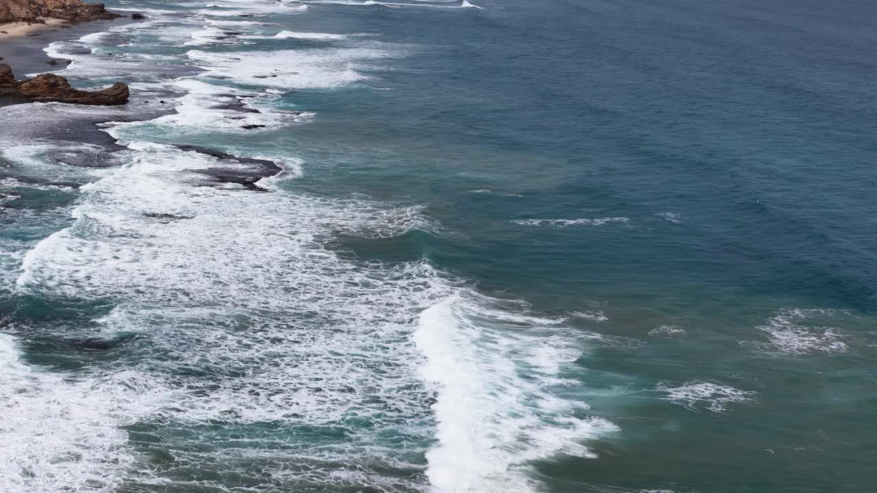 Riprese di un drone sulle onde che si infrangono e sulla costa rocciosa alla luce naturale lungo la costa di Sorrento, Victoria