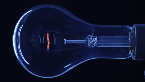 bombilla transparente bajo luz ambiental azul que se enciende a pleno brillo