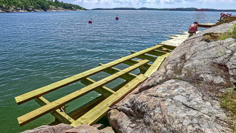 timelapse of some people building a wooden step next to the sea water