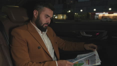 man working with papers in backseat of car