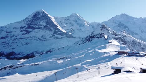 una hermosa zona de esquí en primer plano, eiger, mönch y jungfrau en el fondo, mucha nieve y sol