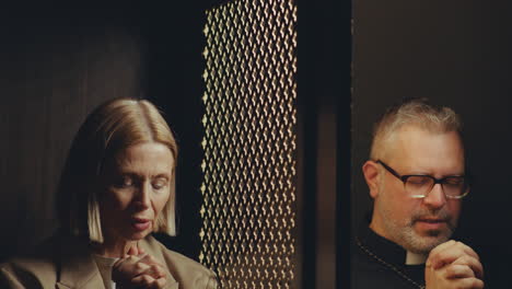 priest and female parishioner praying to absolve sins in confession