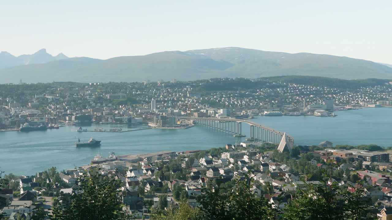 Stunning Aerial View of The City of Troms&oslash; on a Sunny Summer Day, with some Traffic on the Bridge and a Cargo Ship in the Foreground, Norway
