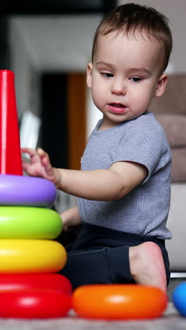 lovely caucasian toddler builds a toy pyramid. happy child growing and developing. vertical video