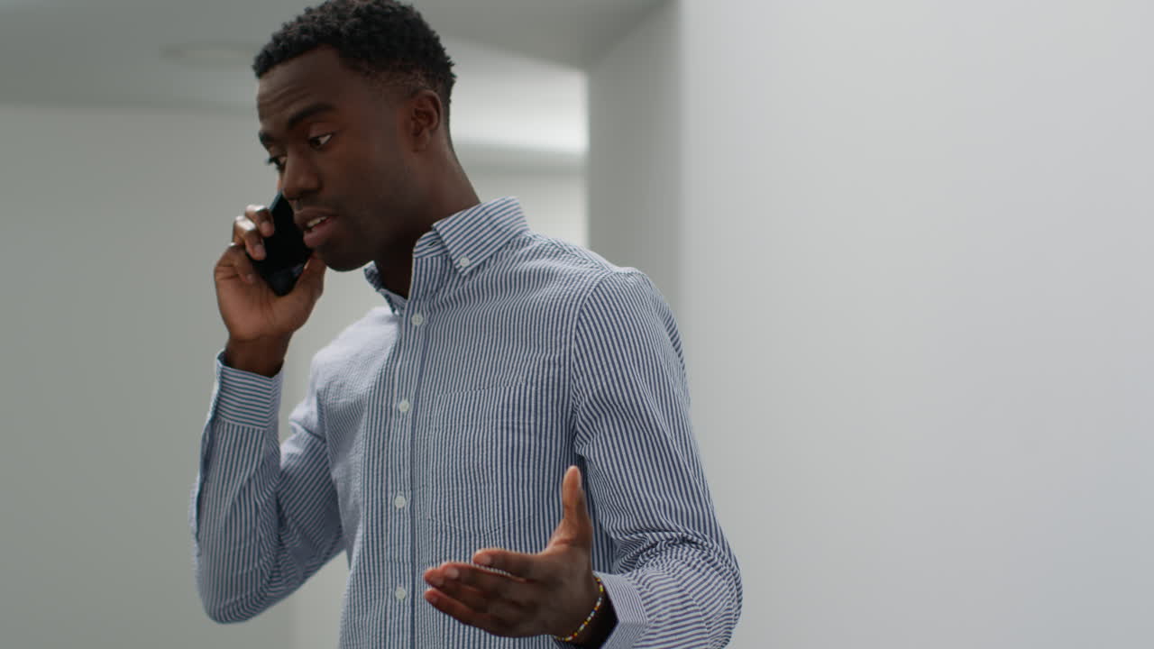 Young Businessman In Office Talking On Mobile Phone Looking Frustrated And Angry 1