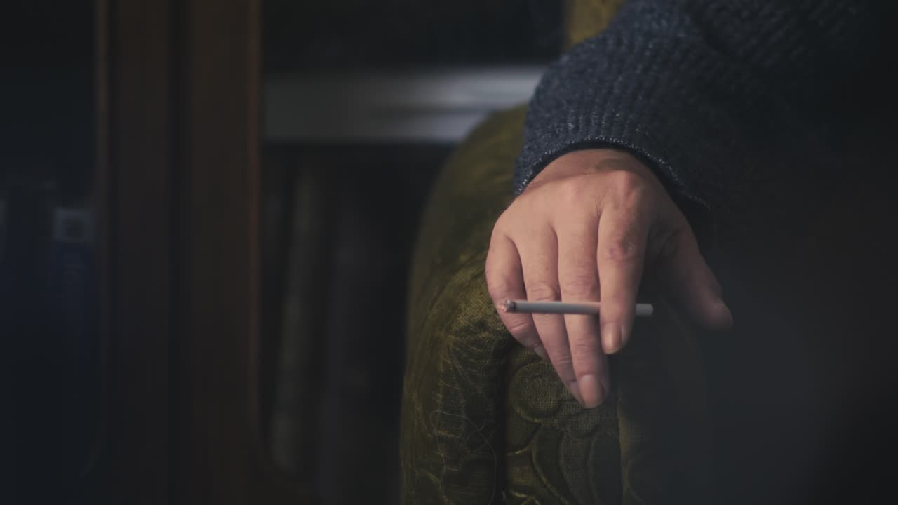 Close-Up of Man’s Hand Holding Burning Cigarette in Armchair