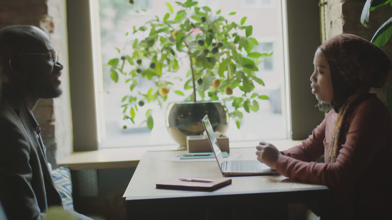 Woman in Hijab Discussing Business with Partner in Cafe