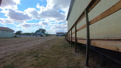 timelapse - yellow building with a ramp in a small town with a view of the street and a couple cars driving by on a cloudy day