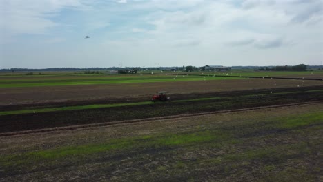 tractor cultivating crops in green paddy fields with birds following it