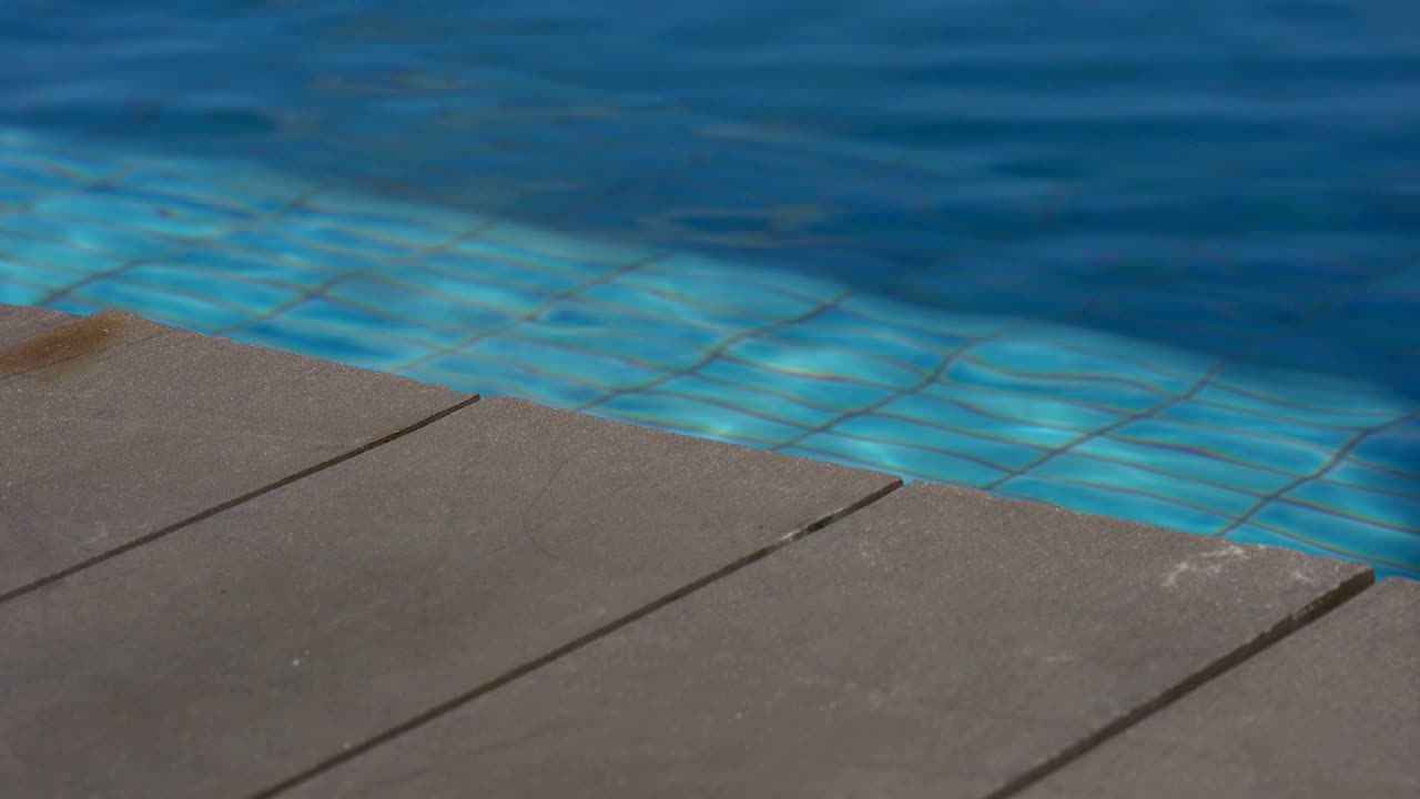 나무 갑판과 파란 모자이크 수영장을 가진 휴가 순간